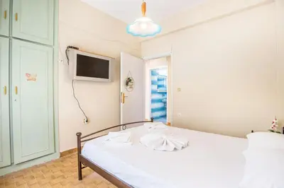 a bedroom with a white bed with a tv on the wall at Ortansia House near the Sea in Ayiá
