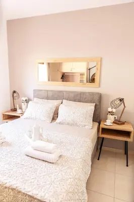 a bedroom with a bed with white sheets and a mirror at Vila Vasiliki, Next To Platanias, 6min From Sea in Vrísai