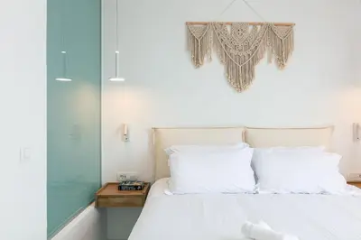 a bedroom with a bed with white sheets and a chandelier at Heniochos Villas in Chania Town