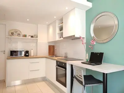 a kitchen with white cabinets and a laptop on a counter at The Garden of Zephyrus - Halepa in Chania Town