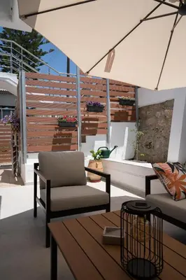a patio with a couch and a table and an umbrella at The Garden of Zephyrus - Halepa in Chania Town