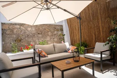 a patio with a couch and a table and an umbrella at The Garden of Zephyrus - Halepa in Chania Town