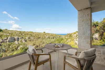 a table and chairs on a balcony with a view of the ocean at Le Mont Blanc - with shared Pool in Kounoupidhianá