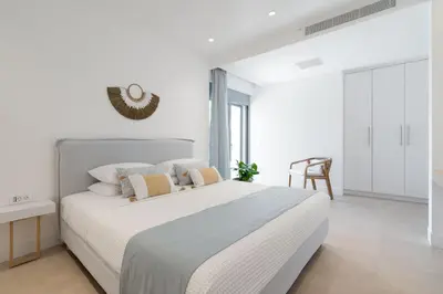 a white bedroom with a large white bed with pillows at Le Mont Blanc - with shared Pool in Kounoupidhianá