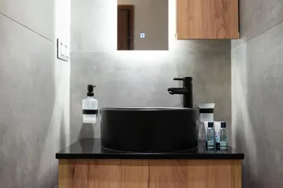 a bathroom sink with a black counter top at Anassa Seaside Residence- 50m from Sandy Beach in Chania Town