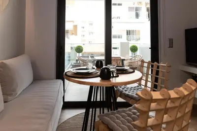 a table and chairs in a living room with a window at Anassa Seaside Residence- 50m from Sandy Beach in Chania Town