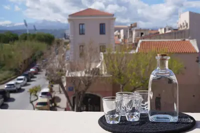 a bottle and three glasses sitting on a table at Venetian Owl, 1min To Lighthouse in Chania Town