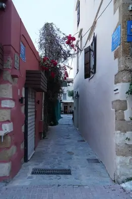 an alley in an old town with flowers at Venetian Owl, 1min To Lighthouse in Chania Town
