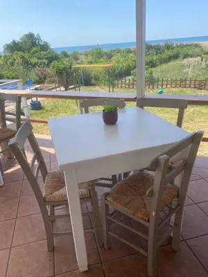 a white table and chairs with a view of the ocean at Artemis Hotel-MeRaki Restaurant in Frangokastello