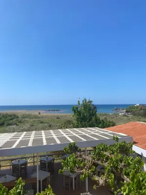 a row of tables and chairs in front of the beach at Artemis Hotel-MeRaki Restaurant in Frangokastello