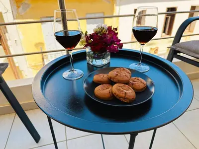 a table with two glasses of wine and a plate of cookies at Cozy Snuggle- 2min To Beach, 6min Walk To Old Town in Chania Town