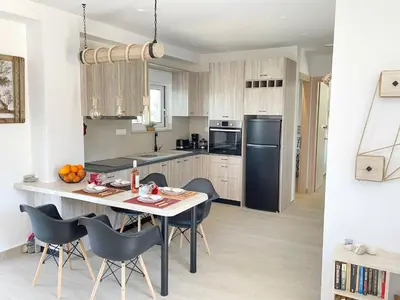 a kitchen with a table and chairs and a black refrigerator at Phaedra House For Relaxing Holidays Near Platanias in Vlakheronítissa