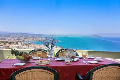 a red table with chairs and a table with a view of the ocean at Koralia - Chanias Card Postal Villa Majestic View in Chania Town