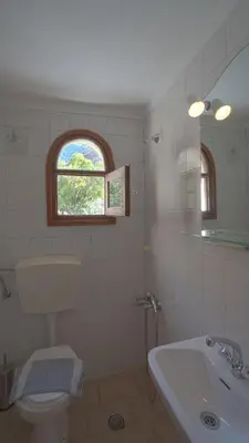 a bathroom with a sink and a toilet and a window at Ilingas Hotel in Khóra Sfakíon