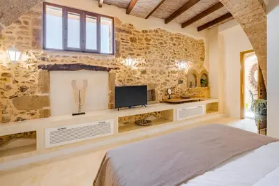 a bedroom with a stone wall with a tv and a bed at Disegno Villa - Rooftop Pool in Kolymvari