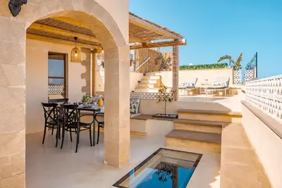 a patio with a table and chairs and a swimming pool at Disegno Villa - Rooftop Pool in Kolymvari