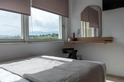 a bedroom with a bed and a mirror and windows at Ros Solis Luxure House in Chania Town
