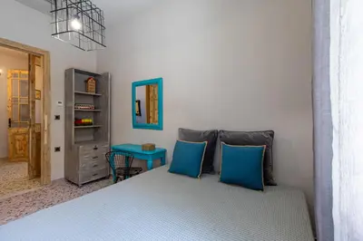 a bedroom with a bed with two blue pillows at Casa di Batsi in Chania Town