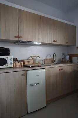 a kitchen with a white refrigerator and wooden cabinets at L A Boutique Suites with Private Hot Tub in Kalathas