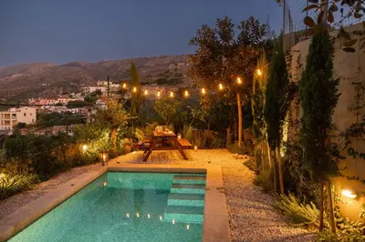 a swimming pool in a yard with a table and lights at Rimondi Residences Chania in Chania Town