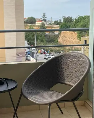 a chair on a balcony with a view of a street at City Spot Chania in Chania Town