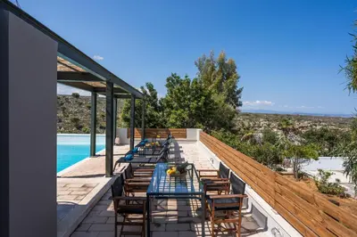 a deck with a table and chairs and a pool at Natura Hill Villa IV Sea View in Kounoupidhianá