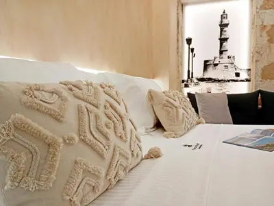 a bed with white sheets and a lighthouse in the background at Domus Vivendi in Chania Town