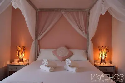 a bedroom with a bed with two lamps on it at Vrachos Apartments in Frangokastello