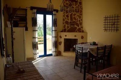 a dining room with a table and a fireplace at Vrachos Apartments in Frangokastello