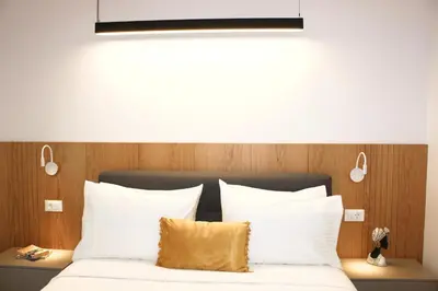 a bed with white pillows and a light above it at Camelia Home in Chania Town