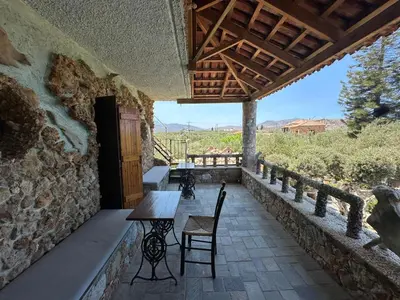 a patio with tables and chairs and a stone wall at Koumos in Kalyves