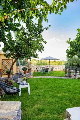 a garden with a table and chairs and a tree at Pomogna house in Pemónia