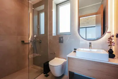 a bathroom with a sink and a toilet and a mirror at Petras Luxury Villas in Falasarna