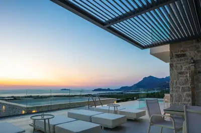 a patio with a view of the ocean at sunset at Petras Luxury Villas in Falasarna