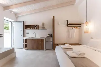 a white room with a bed and a kitchen at Evge Experience Boutique Hotel in Kafoúros