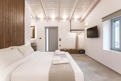 a bedroom with a large white bed and a television at Evge Experience Boutique Hotel in Kafoúros