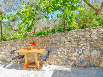 a wooden table and chairs in front of a stone wall at Fully renovated Studio in Platanias in Plataniás