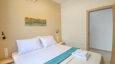 a bedroom with a white bed with a picture on the wall at Fully renovated apartment in Platanias 1 in Plataniás