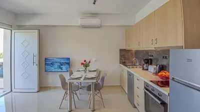 a kitchen with a table and a white refrigerator at Fully renovated apartment in Platanias 1 in Plataniás