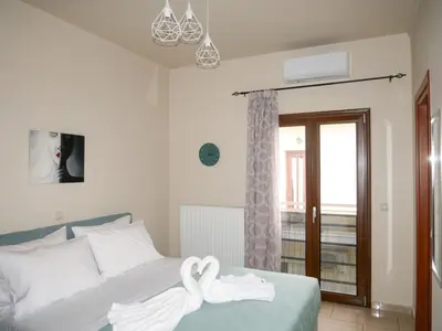 a bedroom with a bed with white sheets and a window at Giovanni City House near Chania City Center in Chania Town