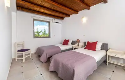 two beds in a room with a window at Villa Vereniki in Áyios Andhréas