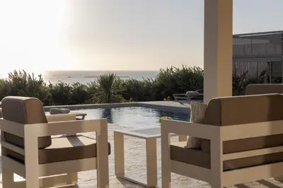 a patio with two chairs and a table and a pool at ALKI VILLAS COLLECTION -LUXURY SEA VIEW VILLAS - BREAKFAST INCLUDED- Falasarna in Falasarna