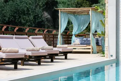 a group of lounge chairs next to a swimming pool at Kotinos Luxury Villa in Chania Town