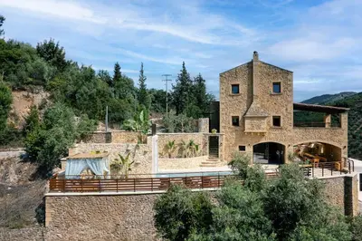 a stone house on a hill with trees at Kotinos Luxury Villa in Chania Town