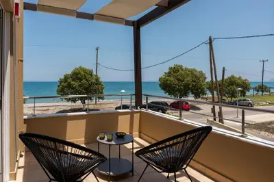 a balcony with two chairs and a table with a view of the beach at Villa Per Mare in Maleme