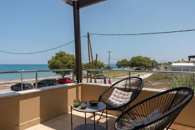 a balcony with two chairs and a table and the ocean at Villa Per Mare in Maleme