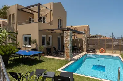 a villa with a swimming pool in front of a house at Villa Per Mare in Maleme