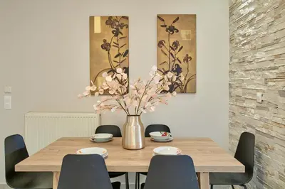 a dining room table with chairs and a vase with flowers at Luxurious house near the sea in Kato Daratso