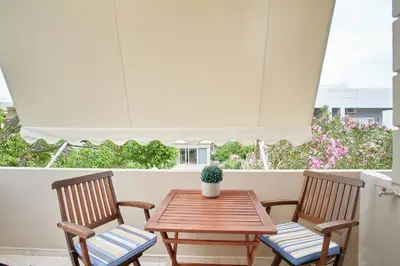 two chairs and a wooden table with a potted plant on a patio at Luxurious house near the sea in Kato Daratso