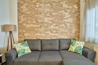 a couch in a living room with a brick wall at Lux and Cozy in Kato Daratso